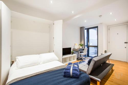 a bedroom with a bed and a chair and a television at Spacious Studio Apartment with private patio near Warren Street in London