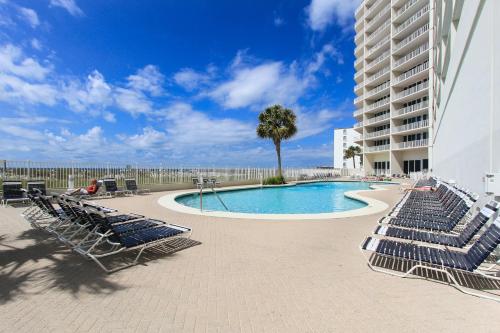 a swimming pool with lounge chairs and a building at Lighthouse 307 in Gulf Shores