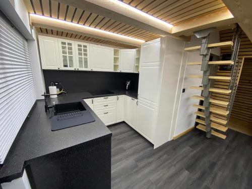 a kitchen with white cabinets and a laptop on a counter at Brunarica Rogla in Vitanje
