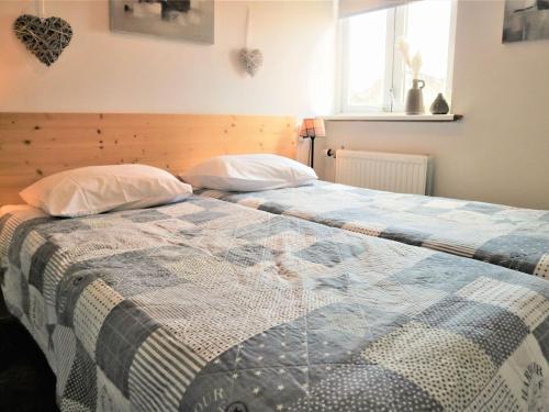 a bed with two pillows and a quilt on it at Apartment in Giethoorn by Scenic Canals in Giethoorn