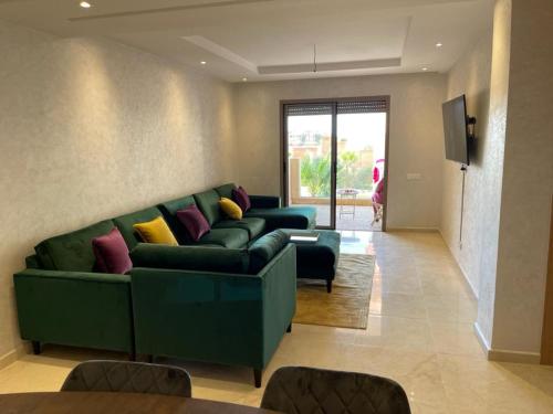 a living room with a green couch with colorful pillows at La Perla de Marrakech Appart de Luxe in Marrakech