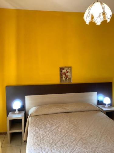a bedroom with yellow walls and a bed with two tables at Hotel La Querceta in Montecatini Terme