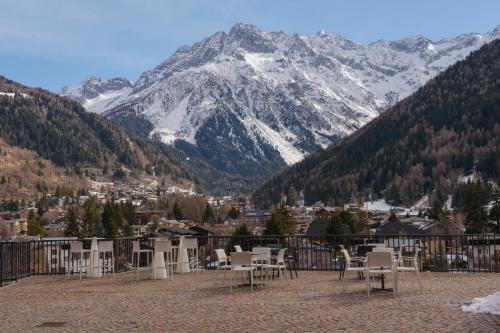 a balcony with tables and chairs in front of a mountain at Hotel Garnì Cristallo in Ponte di Legno