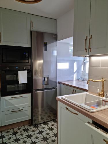 a kitchen with white cabinets and a stainless steel refrigerator at Mistral przy plaży Domki całoroczne in Ustka