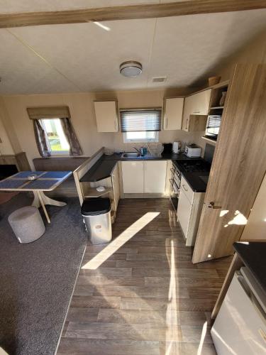 a kitchen with white cabinets and a table in it at K & K Caravan Southview in Skegness