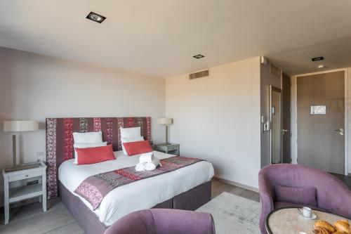 a bedroom with a bed and two purple chairs at Résidence Premium Le Bénétin- Saint Malo in Saint Malo