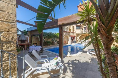 a patio with white chairs and a swimming pool at Authentic Gozitan House sleeping up to 21! in Xewkija