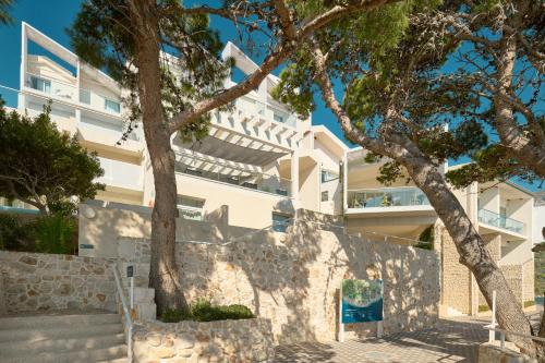 a white building with a tree in front of it at TUI BLUE Makarska - Adults Only in Igrane