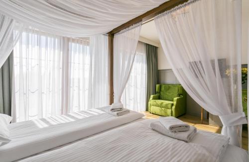 a bedroom with two beds with curtains and a green chair at Nordowi Dwór in Celbowo