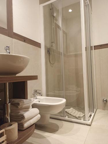 a bathroom with a shower and a toilet and a sink at Post Hotel Moena in Moena