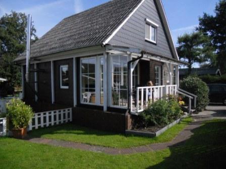 a small black house with a porch and windows at Ferienwohnung Ambiente in Bedekaspel