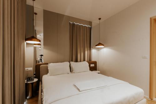 a bedroom with a large white bed with two pillows at Sharm Hotel Luxury in Gjirokastër