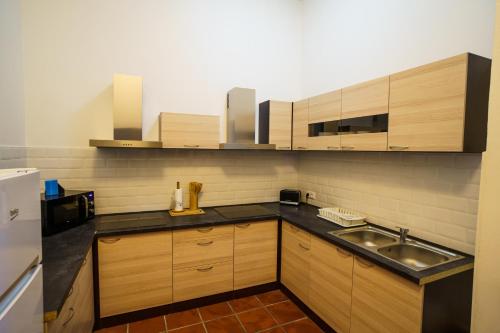 a kitchen with wooden cabinets and a stainless steel sink at Penzion Bílek in Chotěboř