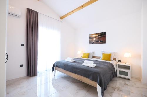 a white bedroom with a large bed with yellow pillows at Timm apartment in Vir