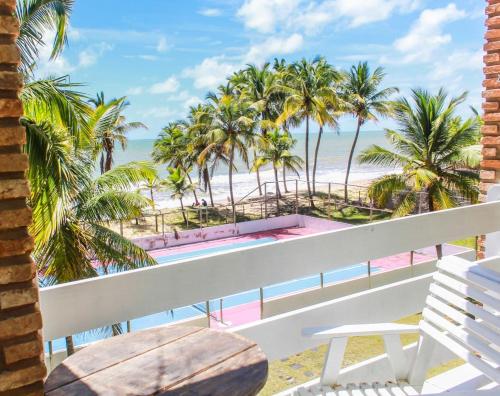 a balcony with a bench and palm trees and the beach at Mar & Sol Praia Hotel in Prado