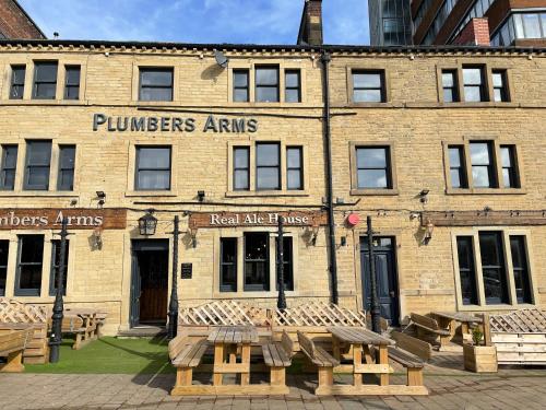 a brick building with tables and benches in front of it at Plumbers Arms in Huddersfield