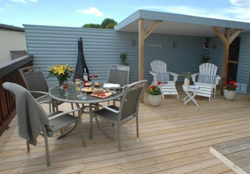 a patio with a table and chairs on a deck at SandPipers Luxury hot tub lodge with 2 ensuites a private Sauna & BBQ terrace in Saint Columb Major