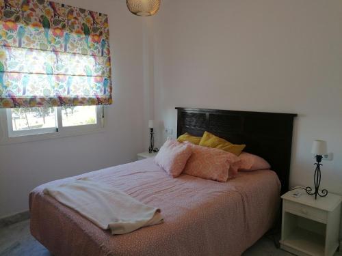 - une chambre avec un lit doté d'oreillers roses et d'une fenêtre dans l'établissement BLUE Dreams, à Mijas