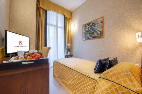 a hotel room with a bed and a desk with a television at Central Park Hotel Modena in Modena