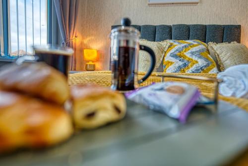 a table with some pastries and a bottle on a couch at Stylish House - B'ham Airport and NEC, JLR Solihull, Business & Leisure Stays - Aspen House in Solihull