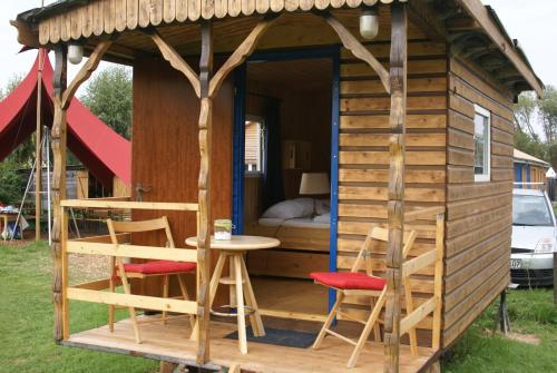 Wakenitz-Camp في Groß Sarau: كابينة خشبية صغيرة بها طاولة وكراسي