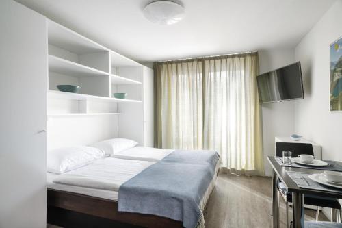 een slaapkamer met een bed, een tafel en een televisie bij Townhouse N26 in St. Moritz