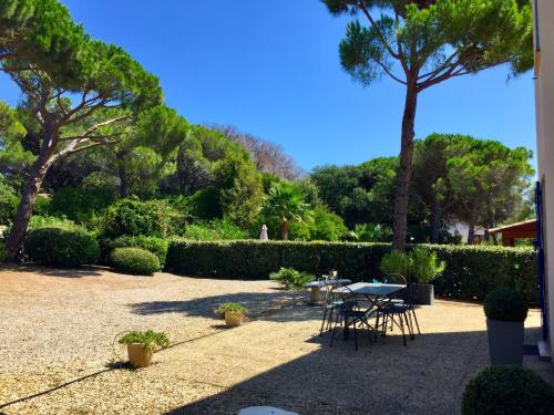a patio with a table and chairs and trees at Holiday Home Le Mas d'Esquières 7 by Interhome in Les Issambres