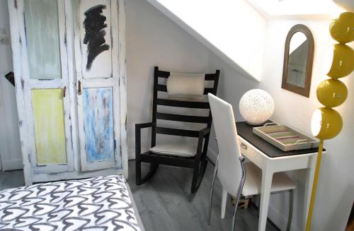 a bedroom with a desk and a chair next to a door at Les petites Mirabelles in Noyers-sur-Cher
