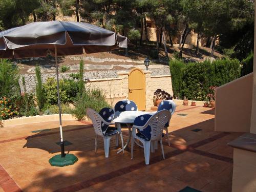 una mesa, sillas y una sombrilla en el patio en Holiday Home Nuidoor by Interhome en Moraira