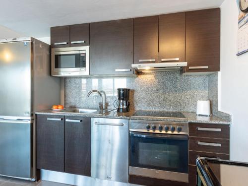 a kitchen with stainless steel appliances and wooden cabinets at Apartment Cap Mestral by Interhome in Roses