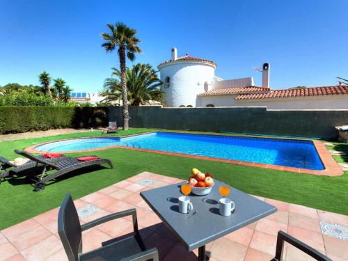 a villa with a swimming pool and a table with a bowl of fruit at Villa Villa Caleta by Interhome in Les tres Cales