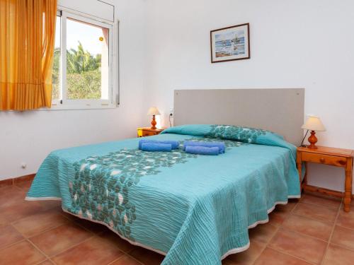 a bedroom with a bed with a blue comforter and a window at Villa Villa Cala Vidre B by Interhome in Les tres Cales