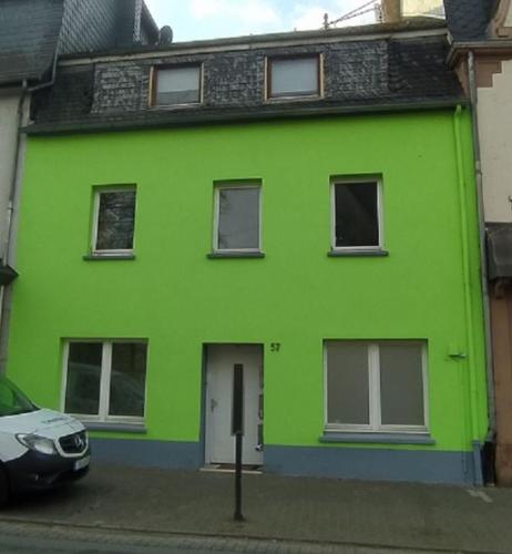 a green house with a car parked in front of it at Ferienwohnung an der Ruwer, Trier in Trier