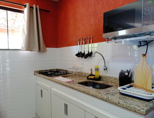 eine Küchentheke mit einer Spüle und einer Mikrowelle in der Unterkunft Apartbuzios - Apartamentos Completos Búzios - 600mt Rua das Pedras in Búzios