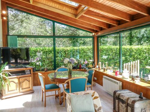 a conservatory with a table and chairs and windows at Holiday Home Villa Pallec by Interhome in Ploemel
