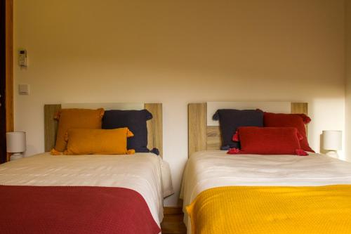 two beds with colorful pillows on them in a room at Casa de Campo Vale do Ceira in Góis