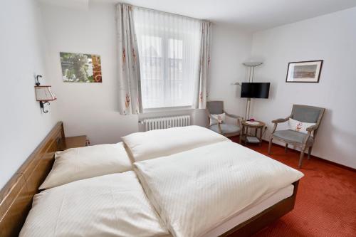 a bedroom with a bed and a window and a chair at Gästehaus Korf in Unkel