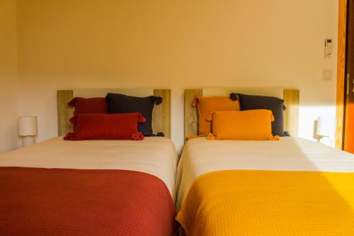two beds with colorful pillows sitting next to each other at Casa de Campo Vale do Ceira in Góis