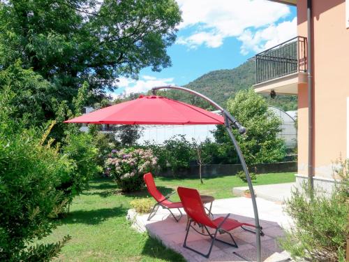 dos sillas rojas y un paraguas en un patio en Apartment Casa dei Fiori by Interhome en Mergozzo