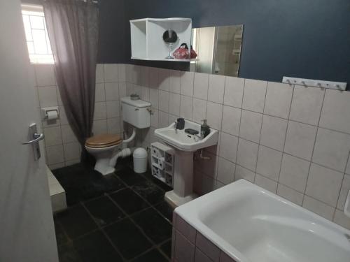 a bathroom with a toilet and a sink at Karoo Refresh Cheerful 2 Bedroom House in Oudtshoorn