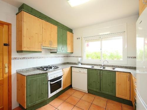 a kitchen with green cabinets and a sink and a window at Villa Villa Cala Nova B by Interhome in Les tres Cales