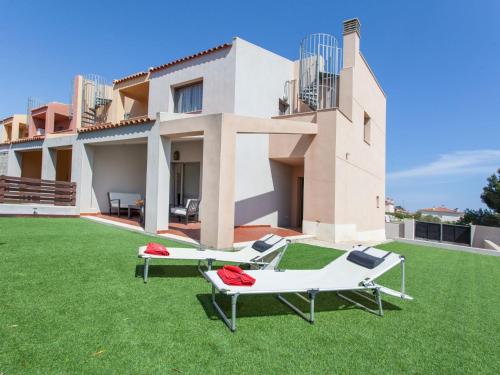 ミアミ・プラトーヤにあるHoliday Home Islas Canarias by Interhomeのラウンジチェア2脚と家のある広い庭