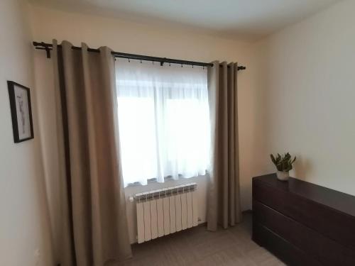 a room with a window with curtains and a radiator at Karczma Karnasów in Cisna