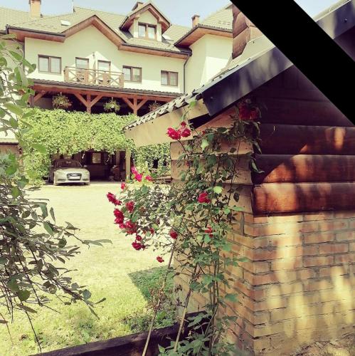 a house with a brick wall and a yard with roses at Karczma Karnasów in Cisna