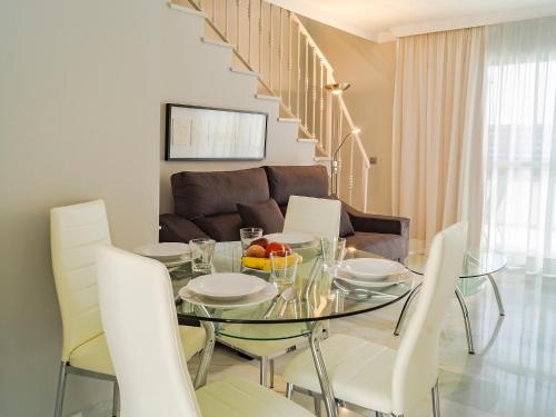 una sala da pranzo con tavolo in vetro e sedie bianche di Apartment La Reserva de Marbella by Interhome a Marbella