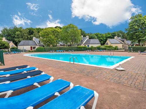 una piscina con sedie a sdraio blu di fronte a una casa di Holiday Home Les Cottages du Golf-3 by Interhome a Ploemel