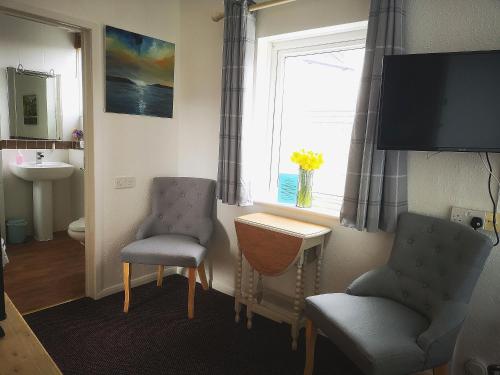 a bathroom with two chairs and a table and a window at Durham House in Beer