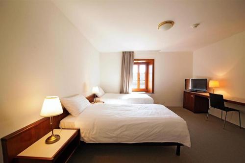 ローザンヌにあるGalion Hôtel & Restaurantのベッド2台とデスクが備わるホテルルームです。
