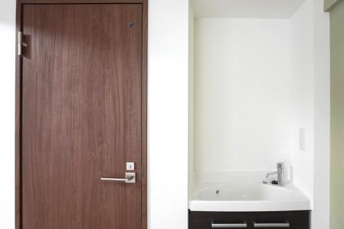 a bathroom with a wooden door and a sink at Tiz 海岸通り in Sumoto