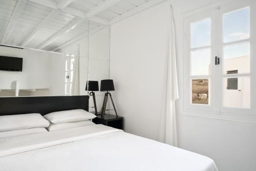 a white bedroom with a bed and a window at Almyra Guest Houses in Paraga